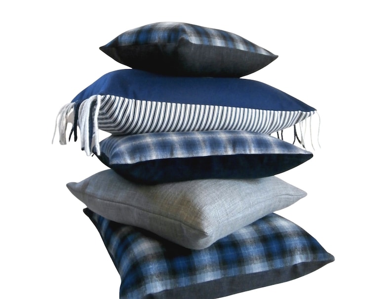 May include: A stack of four blue and white patterned throw pillows. The pillows are arranged in a pyramid shape, with the largest pillow at the bottom and the smallest pillow at the top.