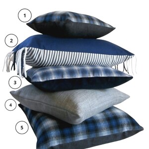 May include: A stack of five blue and black patterned throw pillows. The pillows are arranged in a pyramid shape, with the largest pillow at the bottom and the smallest pillow at the top.