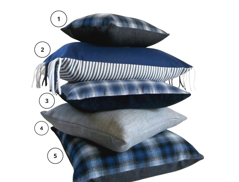 May include: A stack of five blue and black patterned throw pillows. The pillows are arranged in a pyramid shape, with the largest pillow at the bottom and the smallest pillow at the top.