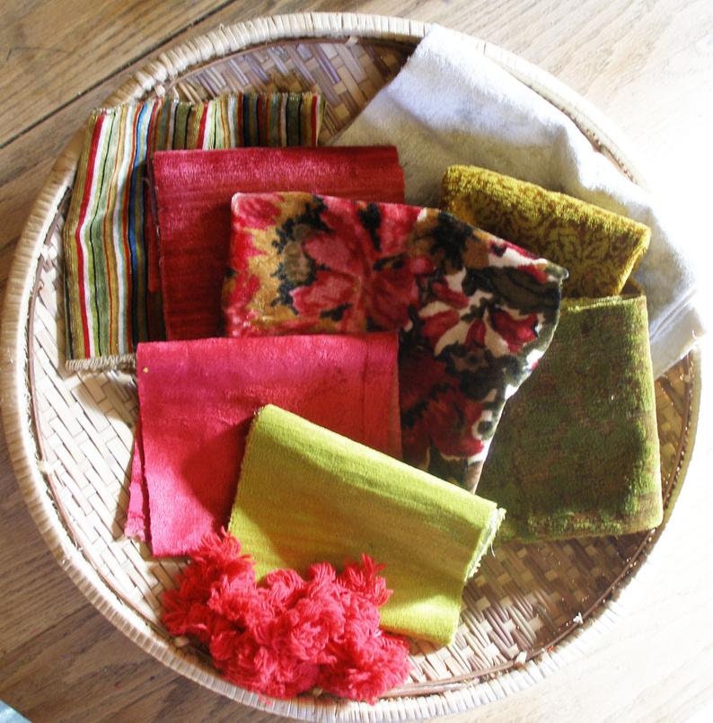 May include: A collection of fabric swatches in a woven basket. The swatches are in various colors and patterns, including red, green, brown, and white.