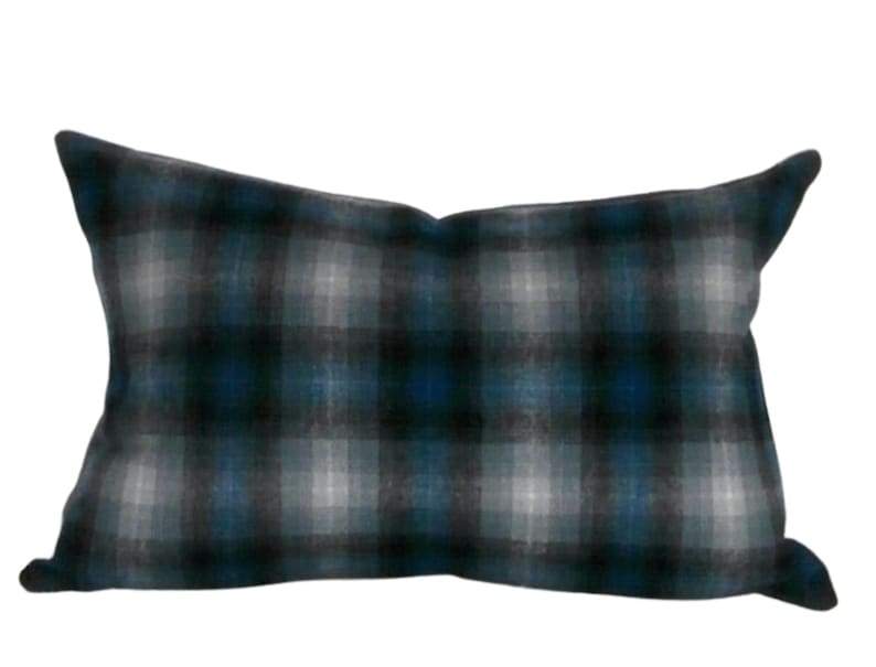 May include: A rectangular cushion with a blue and grey plaid pattern. The cushion is made of a soft, textured fabric.
