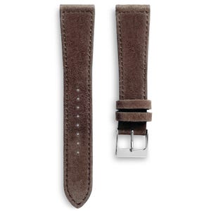 May include: Two brown suede watch straps with a silver-colored buckle. The straps are a medium brown color and have a soft, textured appearance. The stitching is visible along the edges of the straps.