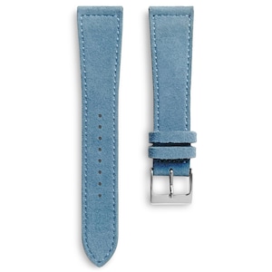 Puede incluir: Dos correas de reloj de ante azul claro con costuras blancas. Una tiene agujeros de ajuste, la otra una hebilla plateada. Las correas están diseñadas para sujetarse a un reloj.