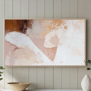 Può includere: Opera d'arte astratta in cornice di legno, con tonalità bianche, marroni e pesca. Sotto, un mobile bianco con gambe dorate ospita una ciotola di legno, vasi e piante, creando un'estetica moderna e minimalista.