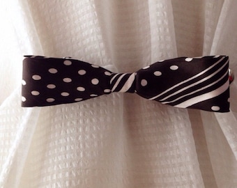 May include: A black and white polka dot and striped fabric bow tie curtain tieback.