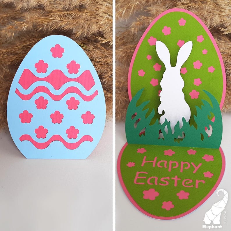 May include: A pop-up Easter card with a blue egg with pink and white designs on the front. The inside of the card has a green egg with a white bunny silhouette and the words "Happy Easter" in pink.