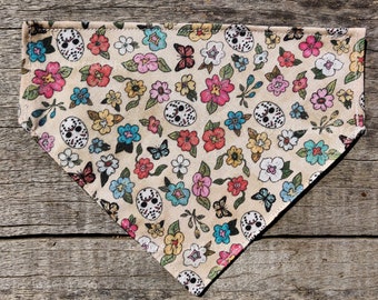 May include: A beige bandana with a colorful pattern of flowers, butterflies, and skull masks.