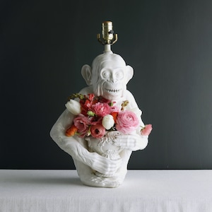 May include: White ceramic monkey lamp with a bouquet of pink and orange flowers in a white ceramic vase.