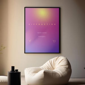 Pode incluir: Uma cena de sala de estar moderna com uma grande cadeira de saco creme, uma mesa lateral preta e um pôster emoldurado com a palavra "DIFFRACTION". O pôster tem um fundo gradiente de rosa, roxo e amarelo. Uma almofada de chão e um vaso preto também são visíveis.