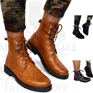 Op de afbeelding: Bruine leren laarzen met brogue details, een vetersluiting en een stevige zwarte zool. De laarzen hebben metalen accenten en worden getoond met een camouflagebroek. Extra laarzen in zwart en bruin worden ook getoond.