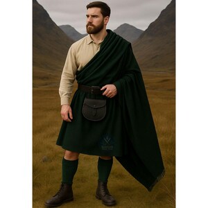 May include: A man in traditional Scottish attire, including a dark green kilt, matching shawl, and knee-high socks. He wears a tan button-down shirt, a black belt with a pouch, and black boots. The background features a mountainous landscape.
