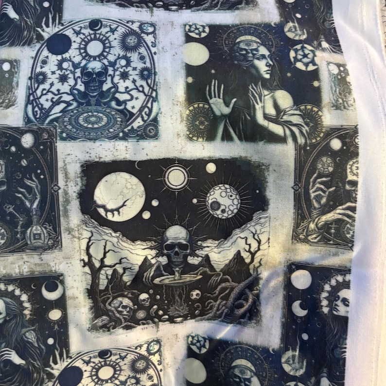 May include: A fabric featuring a repeating pattern of celestial and gothic imagery. The design includes skulls, moons, stars, and figures in a palette of black, white, and teal. The overall theme suggests a mystical or occult aesthetic.