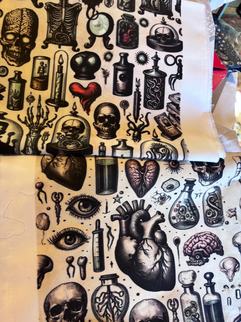 May include: Fabric with a repeating pattern of anatomical and gothic illustrations. Skulls, hearts, brains, eyes, and potion bottles are depicted in black and white with red accents. The fabric has a cream-colored background.