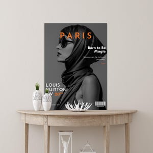 Peut inclure: Une couverture de magazine en noir et blanc avec une femme portant un foulard et des lunettes de soleil. Le texte sur la couverture est "Paris", "Born to Be Magic", "Louis Vuitton", et "W 20".