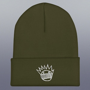May include: A green knitted beanie with a white embroidered logo of a cartoon face with a crown of spikes.