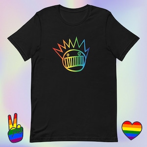 Puede incluir: Camiseta negra con un gráfico de arcoíris de una cara con pelo puntiagudo. El diseño es una ilustración estilizada con un esquema de color arcoíris. Un signo de la paz y un corazón, ambos en colores del arcoíris, están en la imagen.