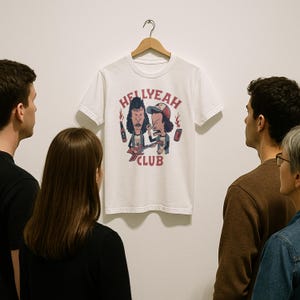 May include: White t-shirt with a graphic print of two cartoon characters playing guitars. The text "HELLYEAH CLUB" is printed below the characters.