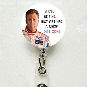 May include: A white and red badge reel with a circular design featuring a photo of Will Ferrell and the text "SHE'LL BE FINE. JUST GET HER A CRISP DIET COKE." The reel has a clear plastic strap and a metal clip.