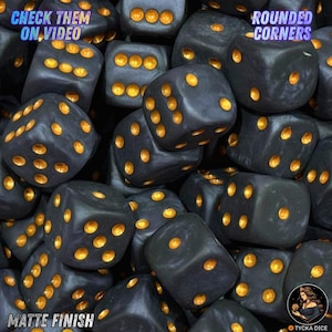 Può includere: Una collezione di dadi a sei facce nero opaco con angoli arrotondati e punti dorati incavati. Il testo CHECK THEM ON VIDEO si trova in alto a sinistra, ROUNDED CORNERS in alto a destra e MATTE FINISH in basso a sinistra.