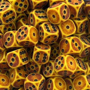 Pode incluir: Uma imagem de perto de uma pilha de dados amarelos com sombreamento castanho e pontos pretos. Os dados estão espalhados, com vários lados visíveis, mostrando as diferentes combinações de números. Os dados parecem ser feitos de um material texturizado.
