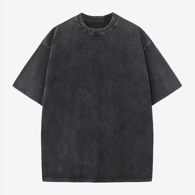 Może przedstawiać: Szary t-shirt z kr&oacute;tkim rękawem i okrągłym dekoltem. Koszulka ma sprany, vintage wygląd. Materiał wydaje się miękki i lekko teksturowany. T-shirt ma luźny kr&oacute;j.