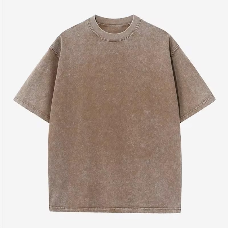 Może przedstawiać: Brązowy t-shirt z kr&oacute;tkim rękawem i okrągłym dekoltem. Koszulka ma wyblakły, teksturowany wygląd. Rękawy są kr&oacute;tkie, a d&oacute;ł prosty. Koszulka wykonana jest z miękkiego materiału.