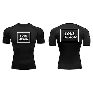 May include: Black compression shirt with short sleeves, shown from the front and back. Each shirt has a white square with the text "YOUR DESIGN" in a sans-serif font.