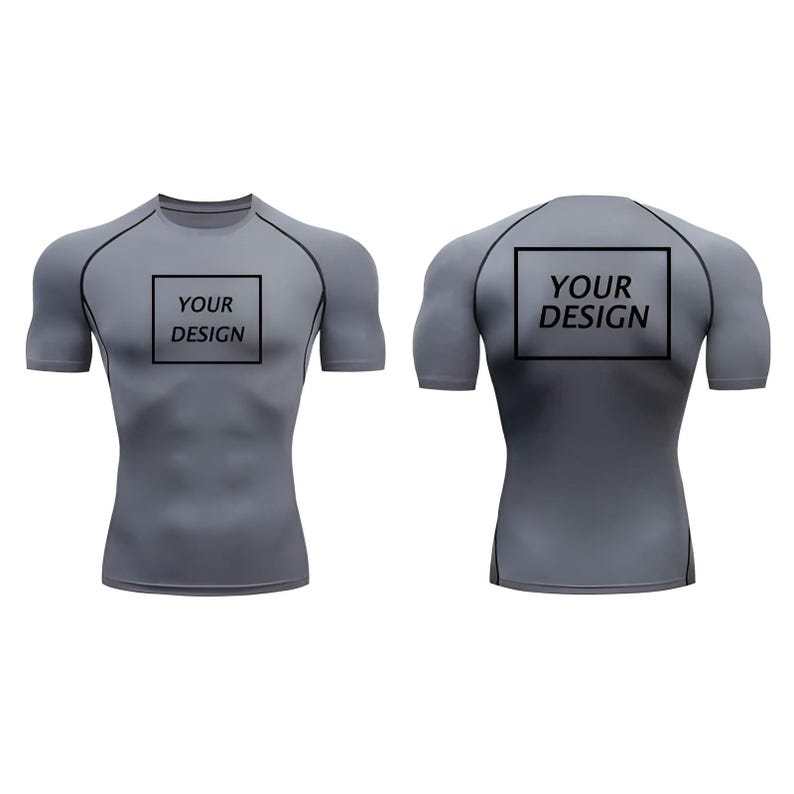 May include: Gray compression shirt with short sleeves, featuring black trim and the text "YOUR DESIGN" in a black box on the front and back. The shirt is designed to fit snugly.