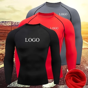 May include: Three long-sleeved athletic shirts in black, red, and gray. Each shirt has a white logo on the chest and contrasting color panels. The shirts are designed for athletic activities and have a form-fitting design.