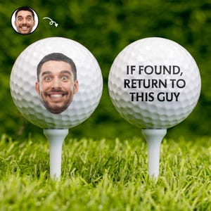 Peut inclure: Deux balles de golf blanches sur des tees dans l'herbe verte. L'une des balles porte le visage d'un homme. L'autre balle porte le texte "IF FOUND, RETURN TO THIS GUY". Une petite image du visage de l'homme est dans le coin supérieur gauche.