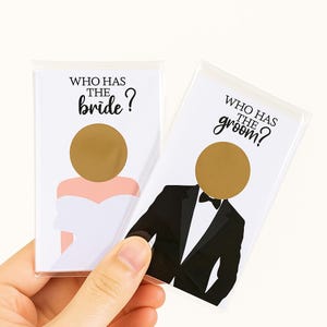 Puede incluir: Dos tarjetas rasca y gana con temática de boda. Una tarjeta presenta una ilustración de novia con el texto "WHO HAS THE bride?" y un círculo dorado. La otra tarjeta muestra una ilustración de novio con el texto "WHO HAS THE groom?" y un círculo dorado.