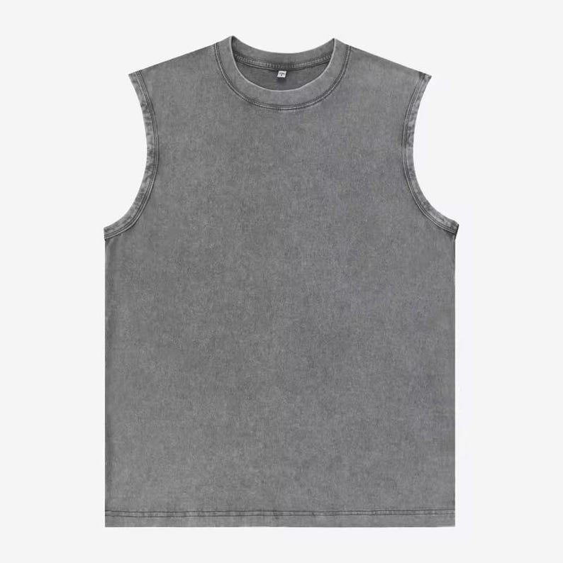 Puede incluir: Una camiseta sin mangas gris con cuello redondo. La prenda tiene un aspecto descolorido y texturizado. Las costuras son visibles y el estilo general es informal y relajado. La camiseta sin mangas est&aacute; hecha de un material suave.