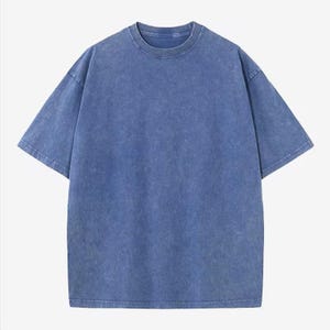 Może przedstawiać: Niebieski t-shirt z kr&oacute;tkim rękawem o wyblakłym, teksturowanym wyglądzie. Koszulka ma okrągły dekolt i luźny kr&oacute;j. Tkanina wydaje się być miękką mieszanką bawełny, odpowiednią do noszenia na co dzień. T-shirt jest w jednolitym kolorze bez widocznych grafik ani wzor&oacute;w.