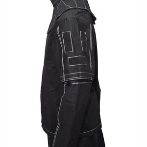 May include: A black jacket with white stitching detail. The jacket has a high collar and a zipper closure. The jacket has two pockets on the front and two pockets on the inside. The jacket is made of a lightweight fabric and is perfect for layering.