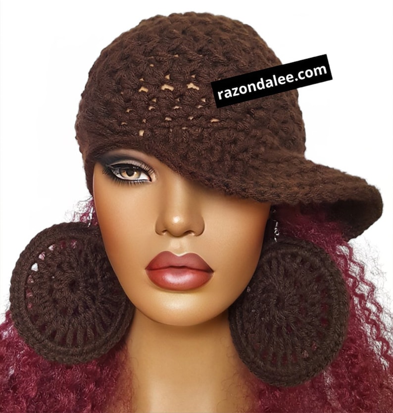 May include: A dark brown crocheted hat with a brim and matching large circular crocheted earrings. The hat features a textured pattern and a black rectangular tag with the white text razondalee.com attached to the side.