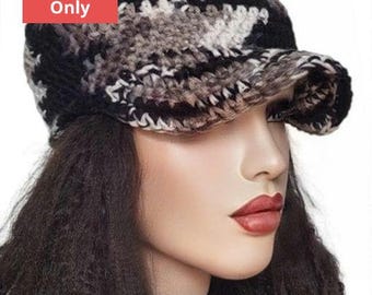 May include: A crochet hat with a black, white, and gray camouflage pattern. The hat has a brim and is worn by a person with long, dark hair.