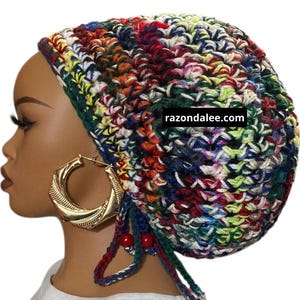 May include: A colorful, crocheted hat in a variety of colors including red, blue, green, and yellow. The hat has a round shape and is worn on the head. The text "razondalee.com" is visible on the hat.