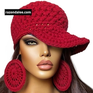 May include: A deep red crocheted baseball cap and matching large circular crocheted dangle earrings. The cap features a textured yarn pattern and a prominent brim. The text razondalee.com is visible in a black box on the cap.