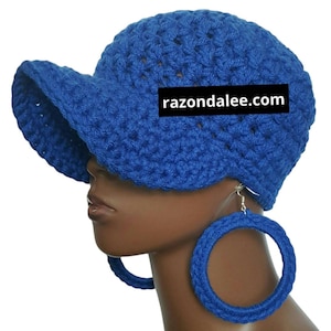 May include: A blue crocheted hat with a brim and matching large hoop earrings. The hat and earrings are a vibrant blue color. The website razondalee.com is printed on the hat.