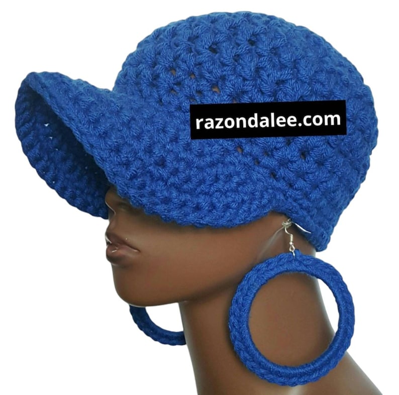 May include: A blue crocheted hat with a brim and matching large hoop earrings. The hat and earrings are a vibrant blue color. The website razondalee.com is printed on the hat.