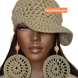 May include: A beige crocheted newsboy cap with a textured pattern and a wide brim, paired with large, circular beige crocheted earrings featuring wooden beads. The text razondalee.com is visible on an orange rectangular background.