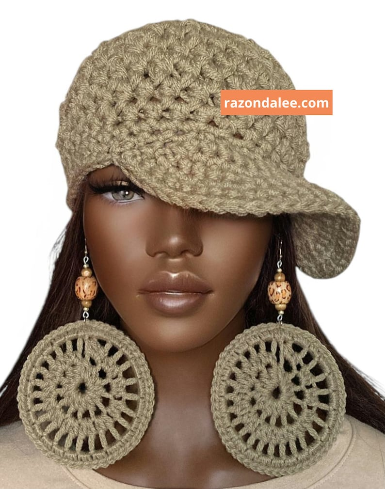 May include: A beige crocheted newsboy cap with a textured pattern and a wide brim, paired with large, circular beige crocheted earrings featuring wooden beads. The text razondalee.com is visible on an orange rectangular background.