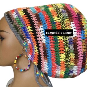 May include: A colorful, handmade crochet hat with a gray brim and attached ties. The hat features a vibrant mix of colors, including pink, yellow, blue, and green. The text "razondalee.com" is visible on the hat.