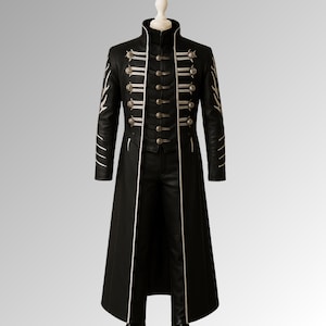 May include: A black, long coat with a high collar and silver button details. The coat features white trim along the edges and sleeves. The coat is displayed on a mannequin.