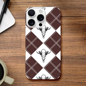 May include: A smartphone case featuring a repeating pattern of dark brown diamonds separated by white diamond shapes. Each white diamond contains a black and white illustration of a cow skull wearing a cowboy hat, centred within the design.