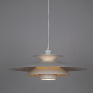 Könnte beinhalten: Eine weiße, mehrschichtige Pendelleuchte mit kreisförmigem Design. Die Leuchte hat eine Reihe von absteigenden, tellerförmigen Schirmen, die einen gestuften Effekt erzeugen. Die Leuchte hängt an einem weißen Kabel und ist beleuchtet.