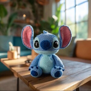 Peut inclure: Une peluche au crochet bleue avec de grandes oreilles dressées aux détails intérieurs roses, une tête ronde et un ventre bleu clair. Le personnage possède deux grands yeux sombres et brillants ainsi qu'un nez bleu foncé en mailles visibles.