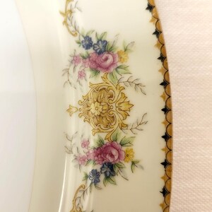 Pu&ograve; includere: Piatto in porcellana color crema con un motivo floreale. Il piatto presenta fiori rosa, blu e gialli con accenti dorati e un bordo decorativo dorato e nero. Un pezzo classico per servire.