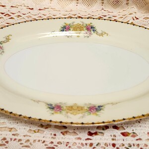 Pu&ograve; includere: Un piatto da portata ovale color crema con bordo dorato e decorazioni floreali. Il piatto presenta un delicato disegno di fiori dorati, rosa, blu e gialli. Il bordo &egrave; rifinito con un motivo a pois neri.