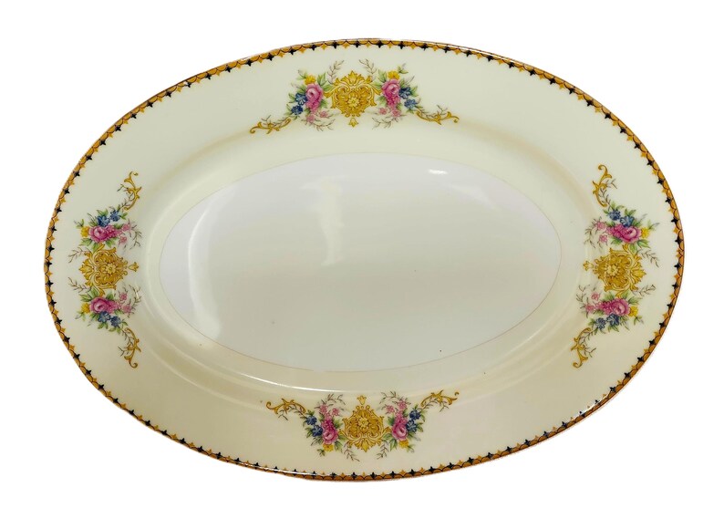 Pu&ograve; includere: Piatto ovale da portata con base color crema e design floreale. Il bordo presenta un bordo dorato con accenti neri. Il motivo floreale comprende fiori rosa, blu e gialli. Un pezzo decorativo per servire il cibo.